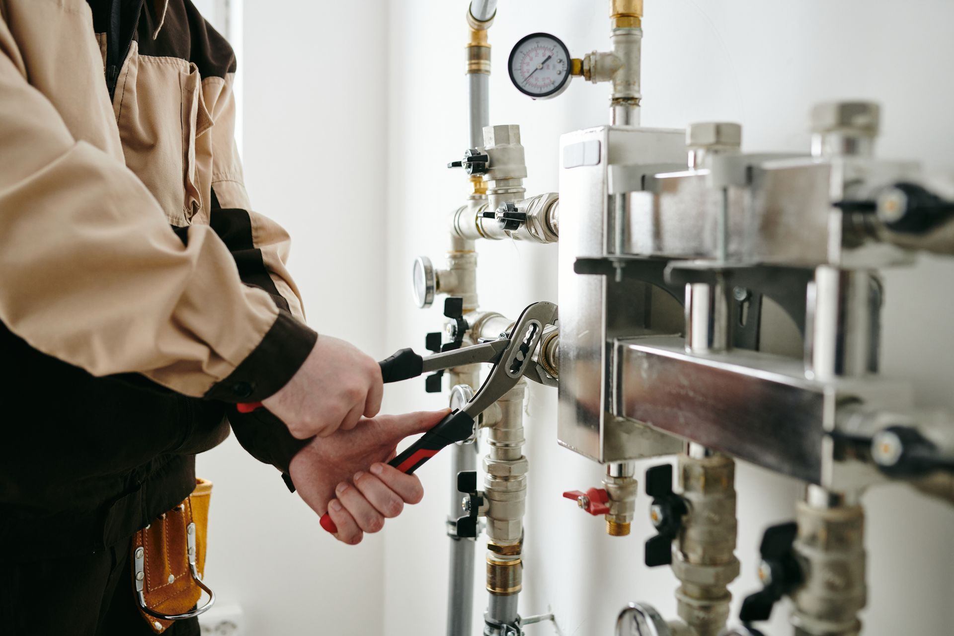 A plumber is working on a pipe with a wrench.