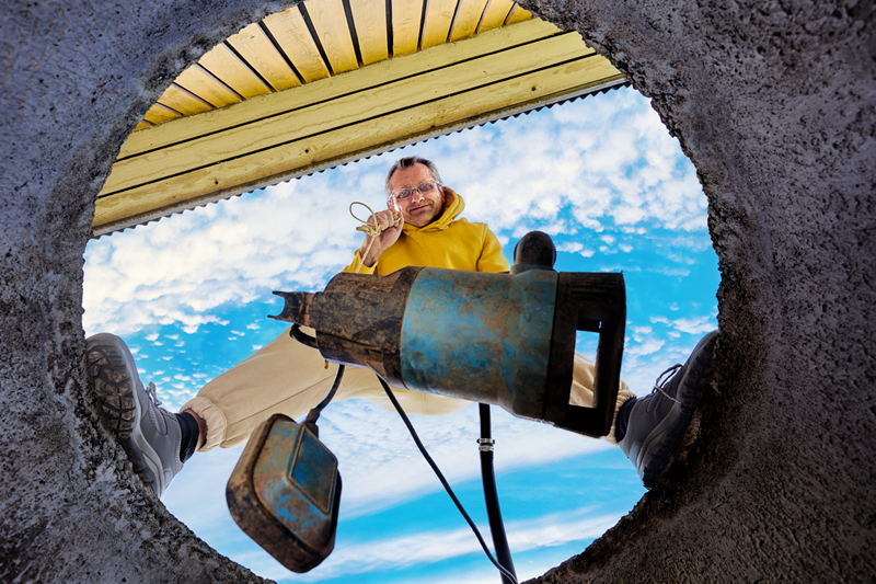 A man is pumping a hose into a septic tank.