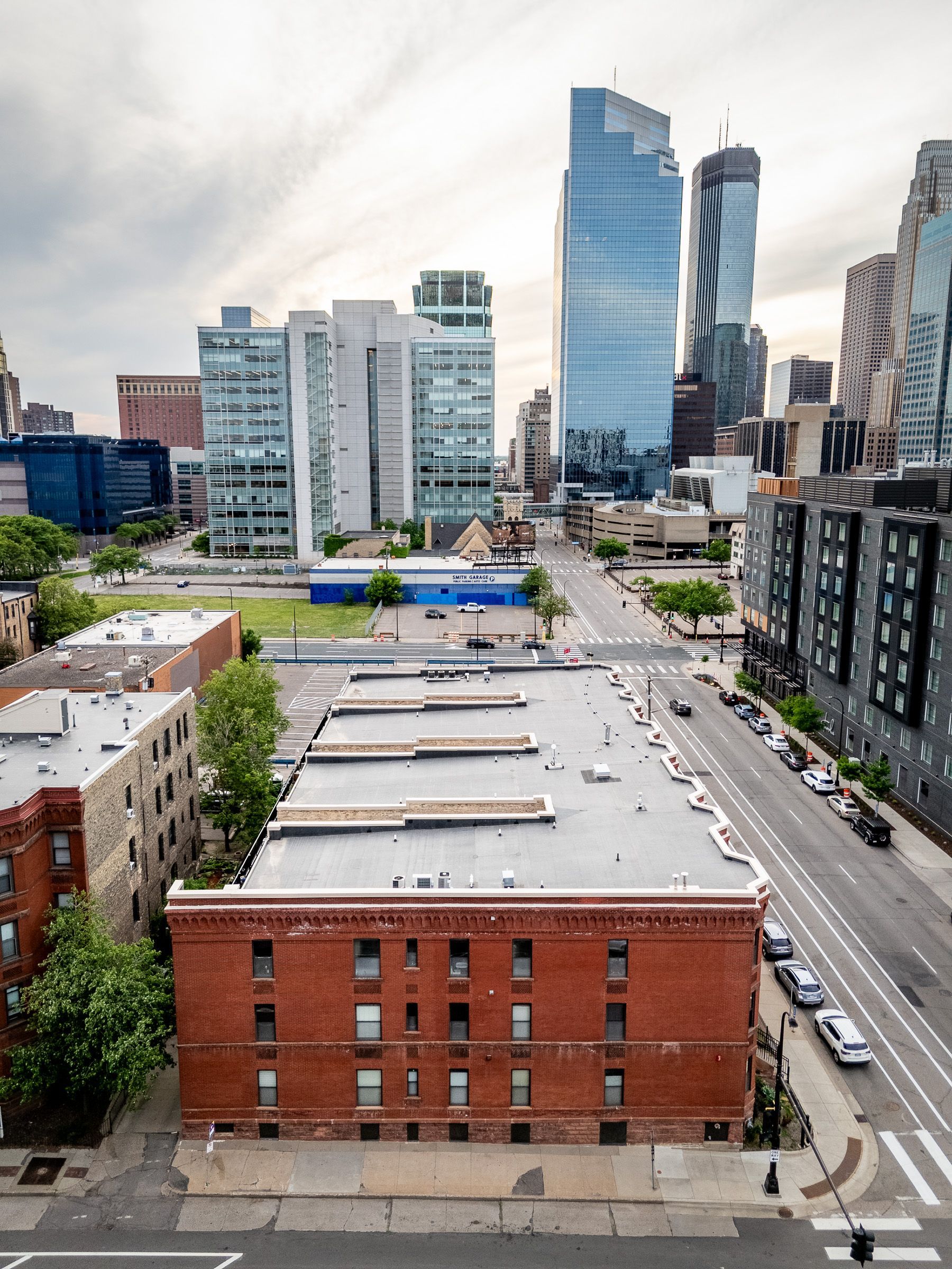 City skyline with modern glass towers behind a red-brick rooftop building and street traffic below