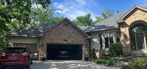 Brick suburban house with a two-car garage, red SUV in driveway, and arched front entryway
