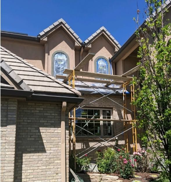 House exterior with brick and stucco facade, dormer windows, and scaffolding in the front yard