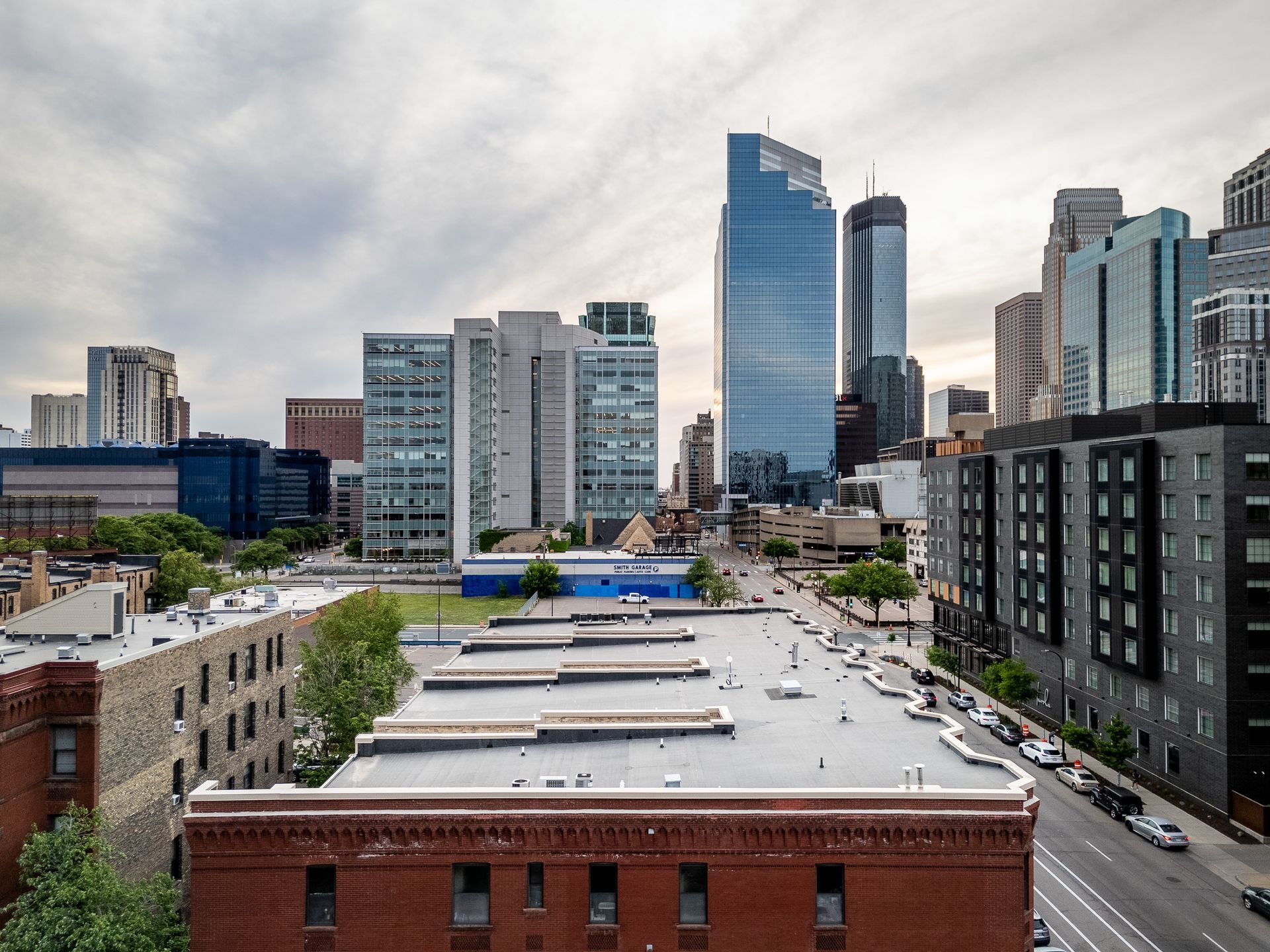 City skyline with modern glass skyscrapers and brick rooftops under a cloudy sky