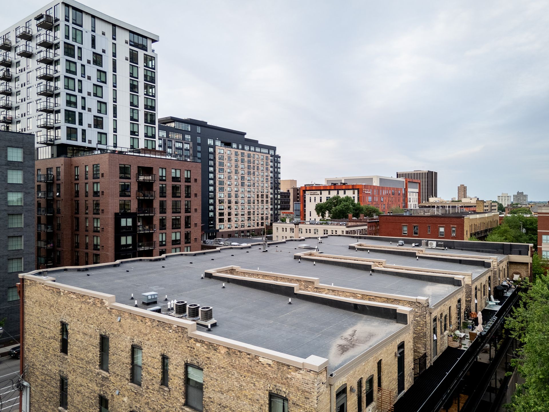 Cityscape with modern apartment buildings and low brick rooftops under a cloudy sky