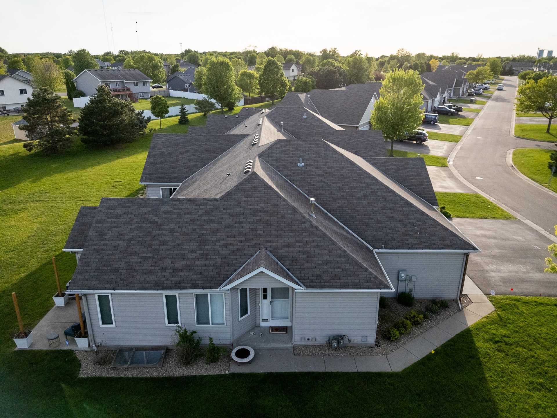 Aerial view of a suburban house with a gray roof on a quiet residential street