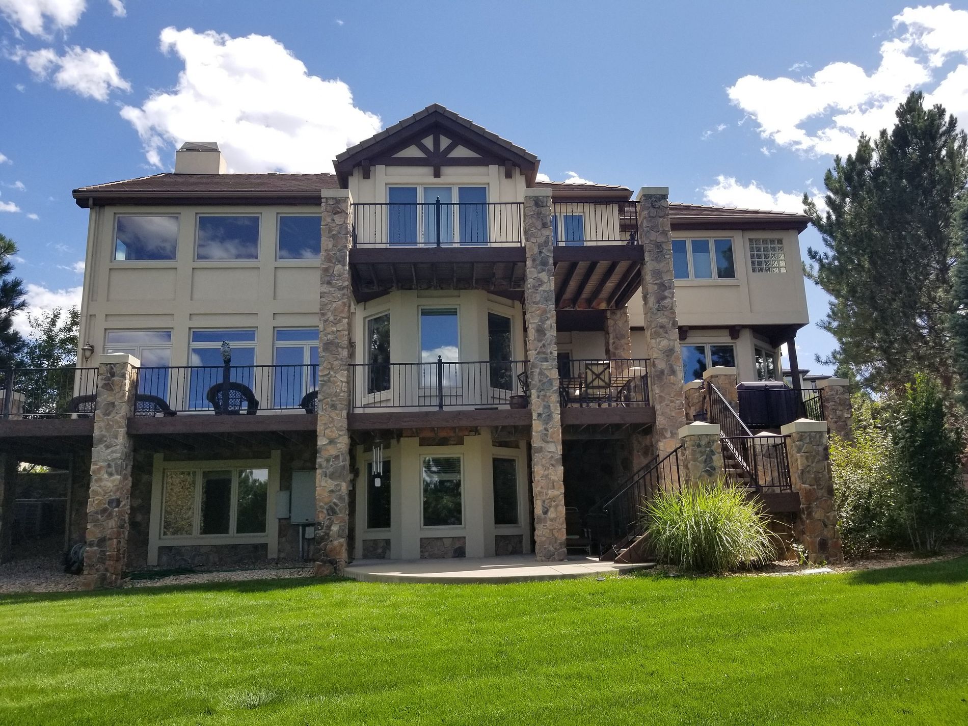 Large stone apartment building with balconies and a grassy lawn under a partly cloudy sky