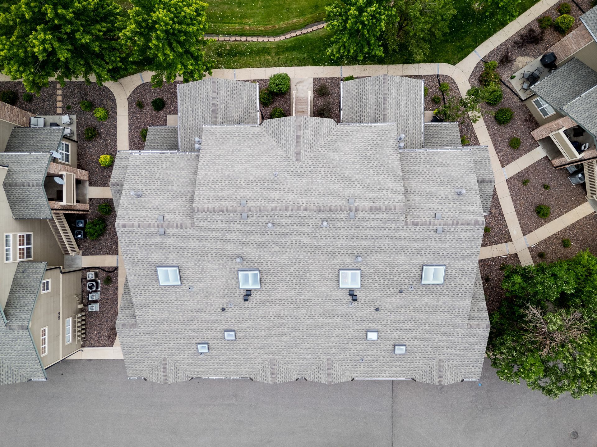 Aerial view of a large gray-shingled house with a landscaped yard and walkways.