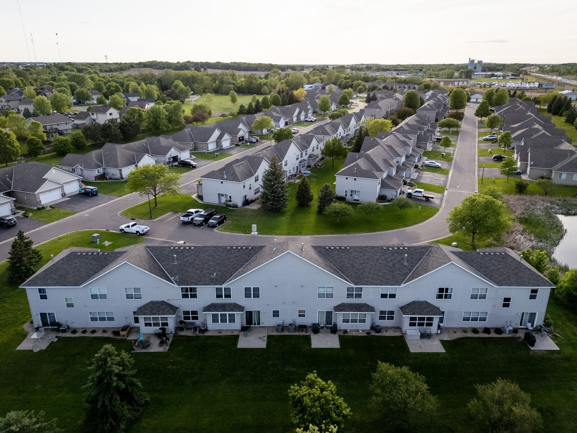 Aerial view of a suburban neighborhood with rows of houses and a white apartment building in front