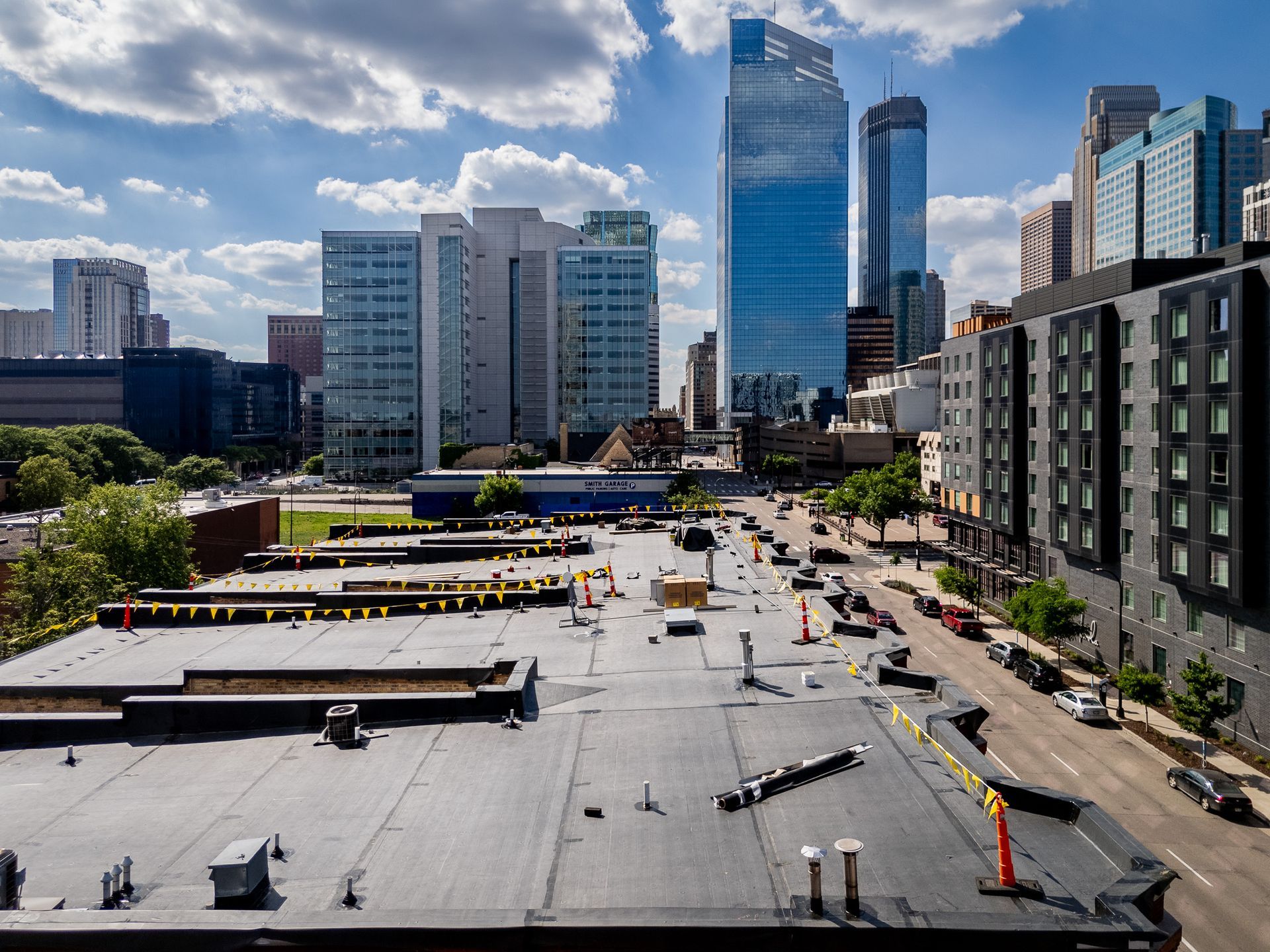 Urban construction site beside modern high-rise buildings under a partly cloudy sky.