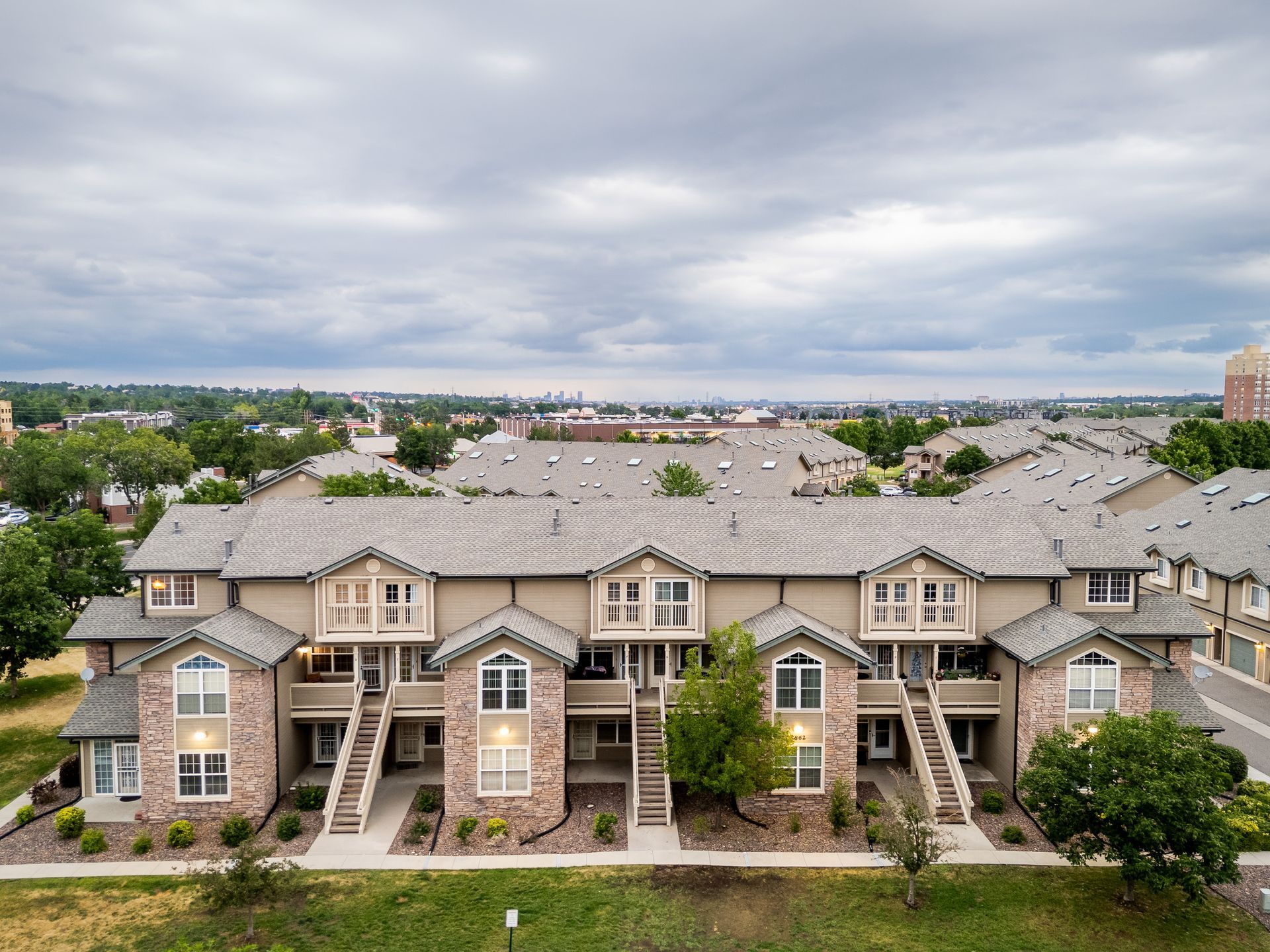 Row of beige apartment townhomes with front balconies under a cloudy sky