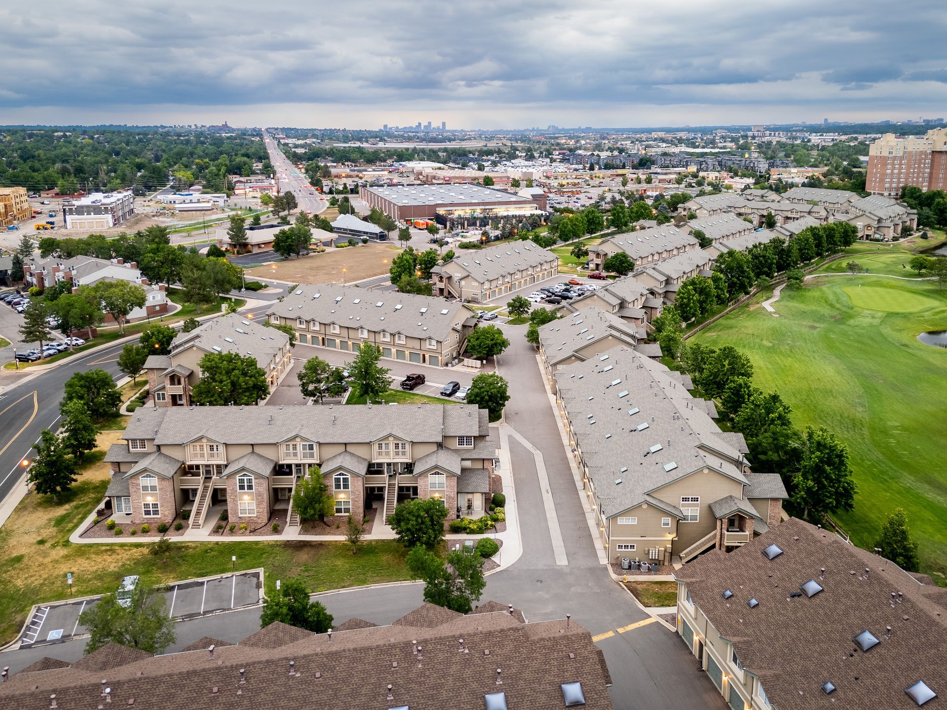 Aerial view of a suburban apartment complex beside a green golf course and tree-lined streets