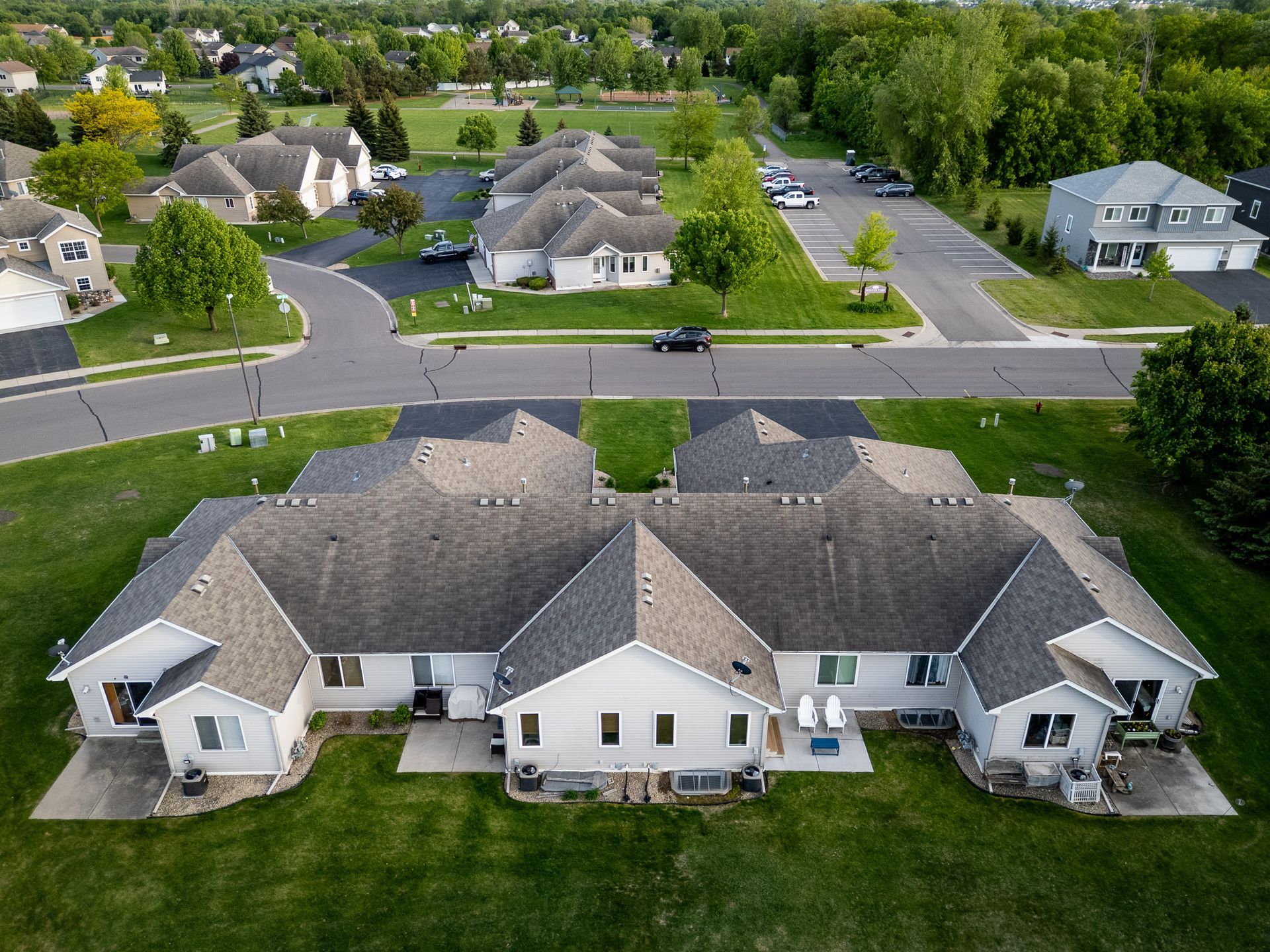 Aerial view of suburban houses and streets with trees and parked cars