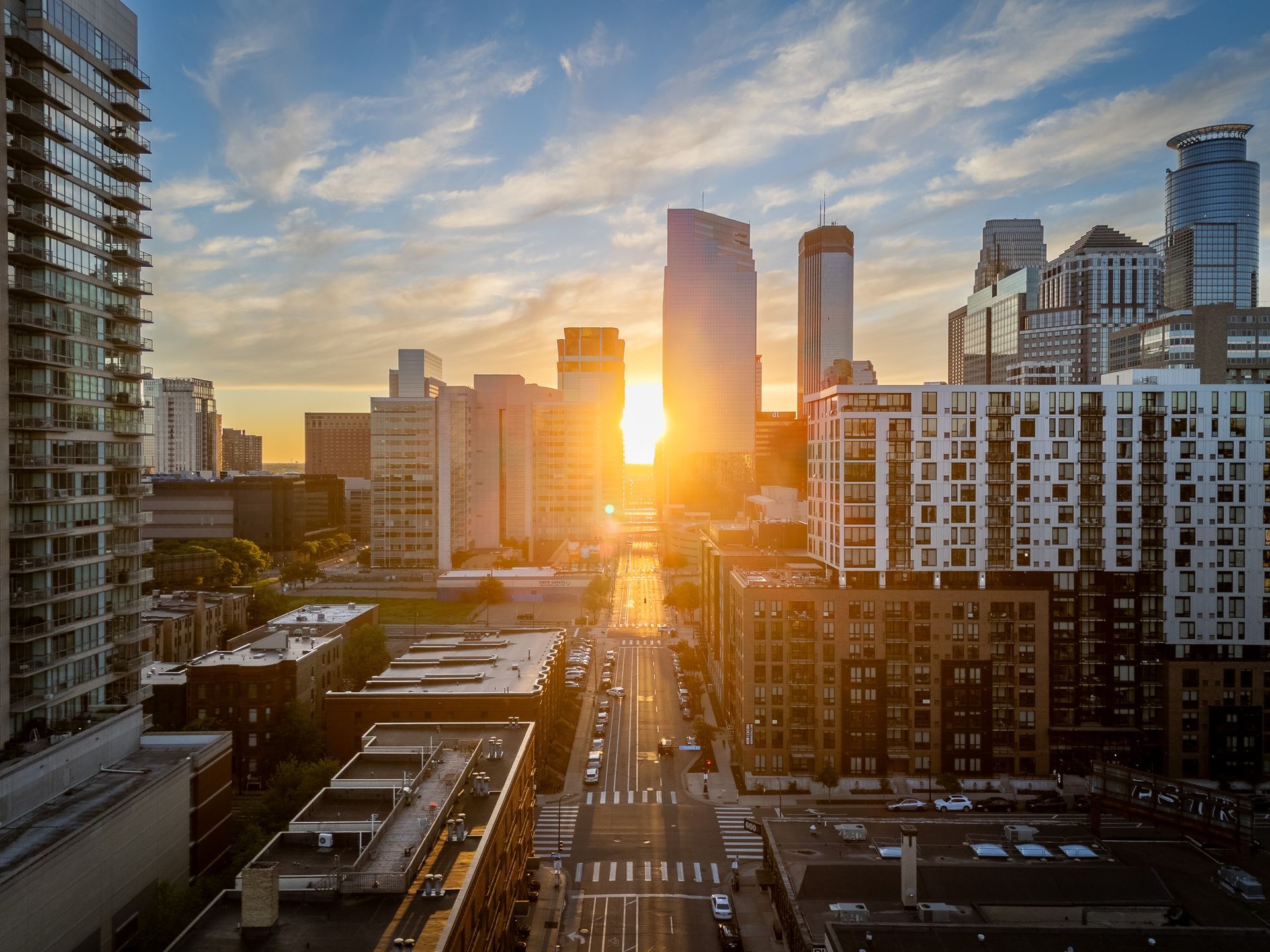 Sunset over a city skyline with tall buildings and a bright sun between towers