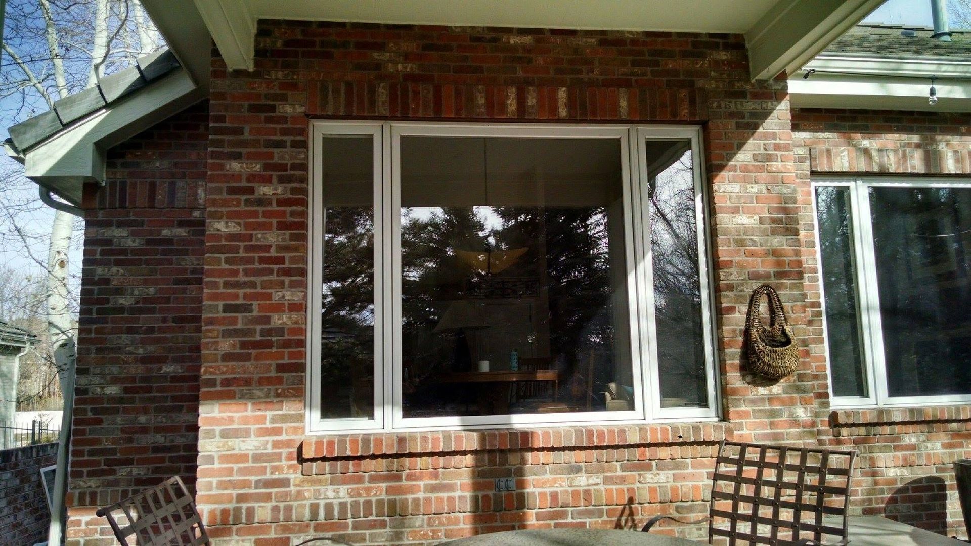 Brick house exterior with a large front window and two patio chairs on the porch