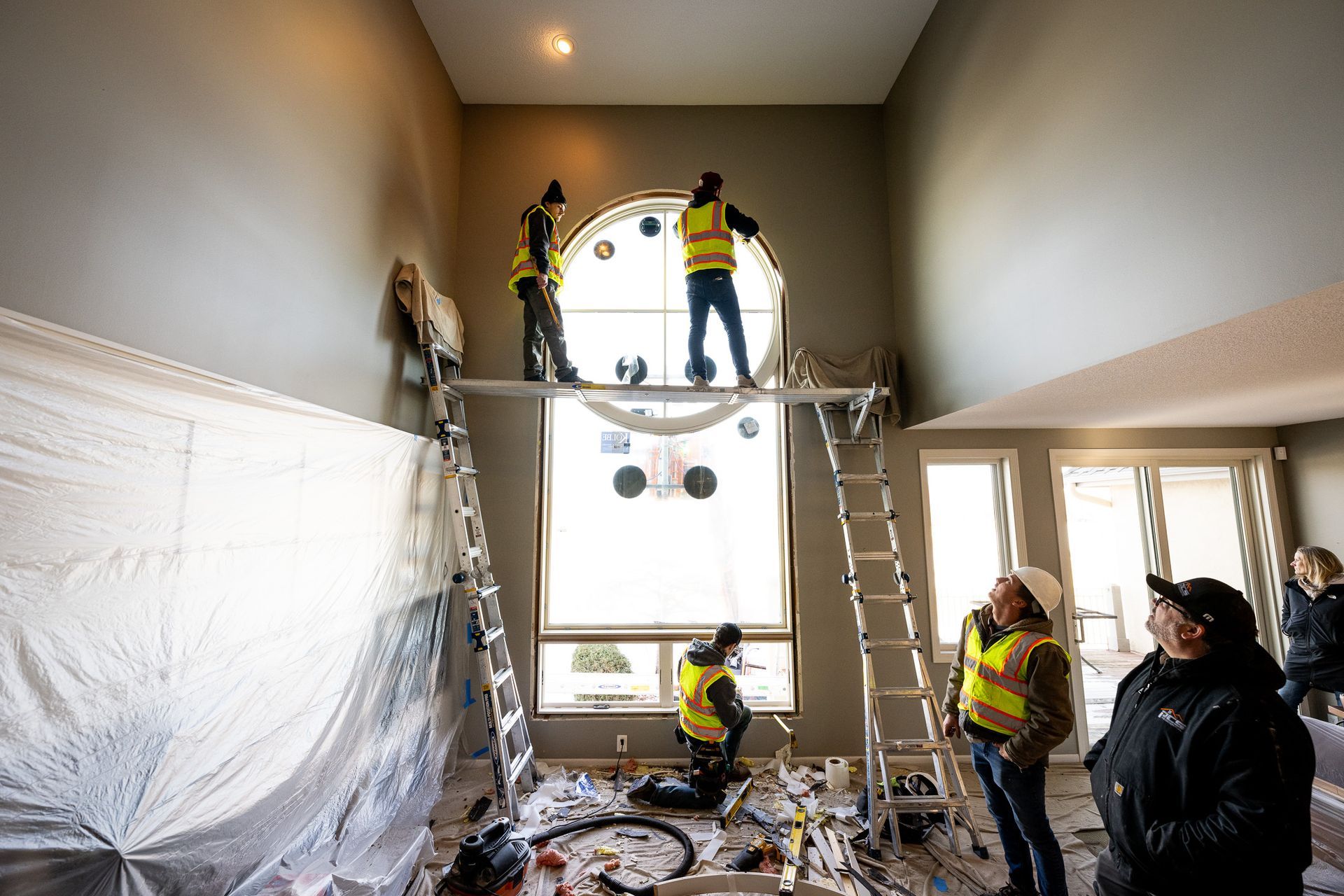 Workers installing a chandelier in a living room during a home renovation