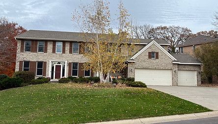 Two-story brick suburban house with a white garage and a lawn in front
