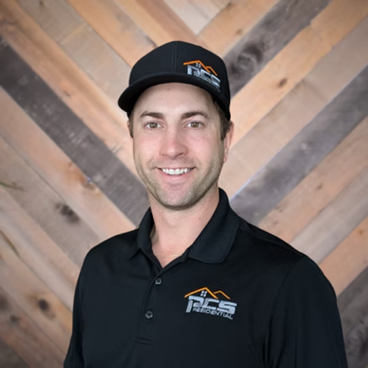 Man in black polo and cap posing before a wood chevron wall
