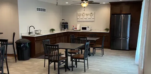 Open kitchen and dining area with wooden table, stools, bar counter, and stainless steel refrigerator