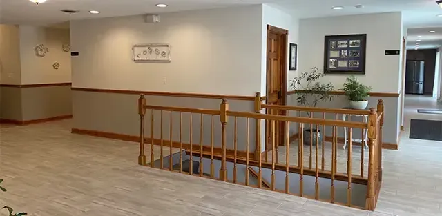 Empty hallway with beige walls, wood railing, and framed wall decor in a building lobby
