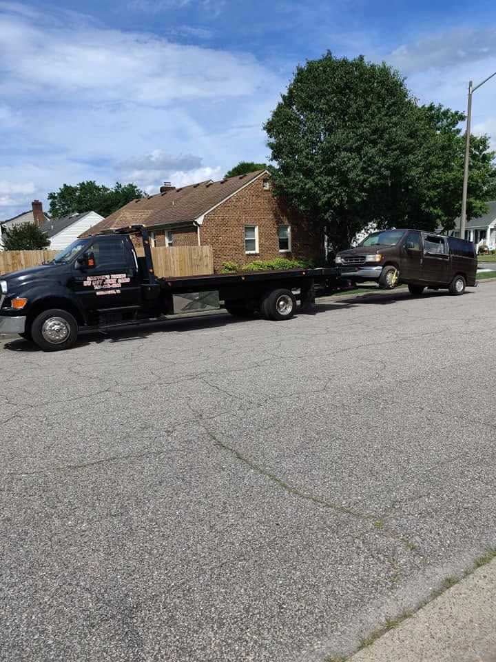 Tow truck hauling a brown house-shaped load on a flatbed in a residential street.