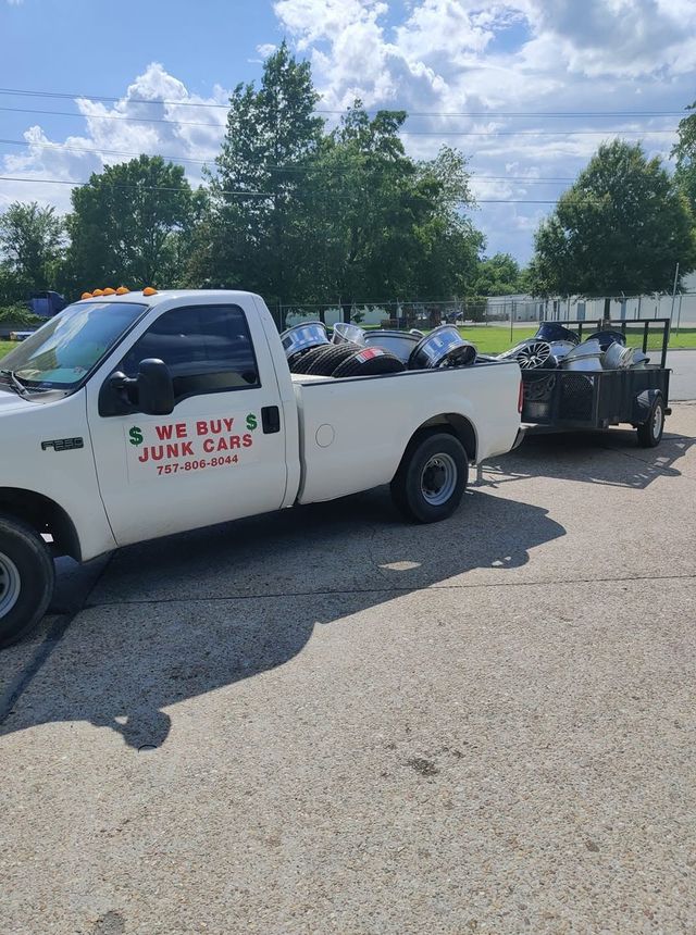 White pickup truck towing a trailer with equipment in a parking lot under a blue sky