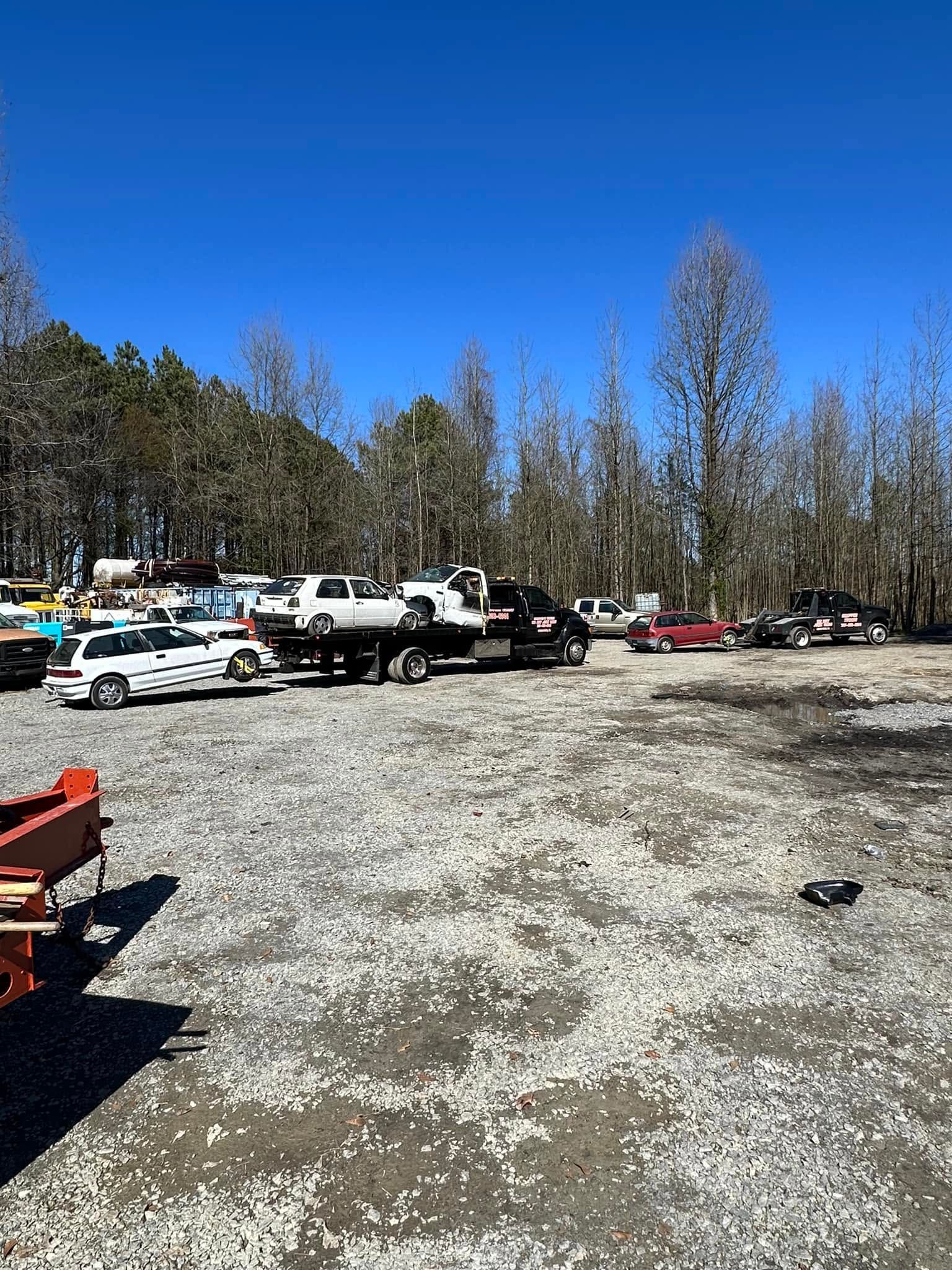 Gravel parking lot with parked cars, leafless trees, and a bright blue sky