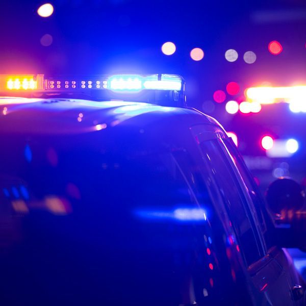 Police cars with flashing red and blue lights at night on a dark street