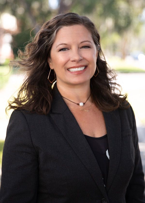 Smiling attorney S. Nicole Jamieson in a black blazer standing outdoors with a blurred background