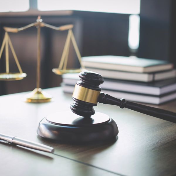 Lawyer’s desk with gavel, scales of justice, and stacked books in soft light