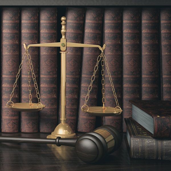Law books, scales of justice, and a gavel on a desk in a legal library