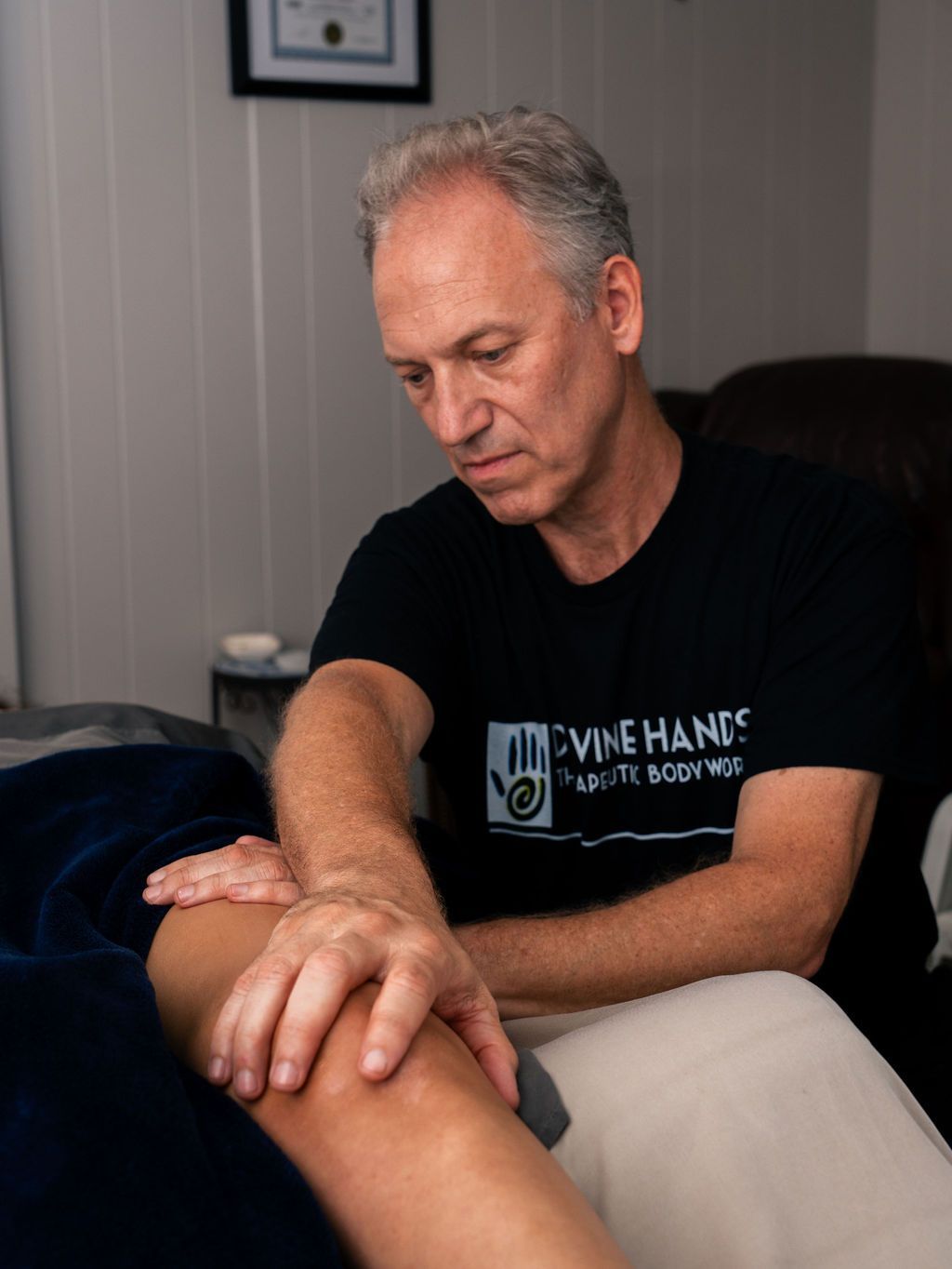Man seated on a couch, gently massaging another person's foot in a living room.