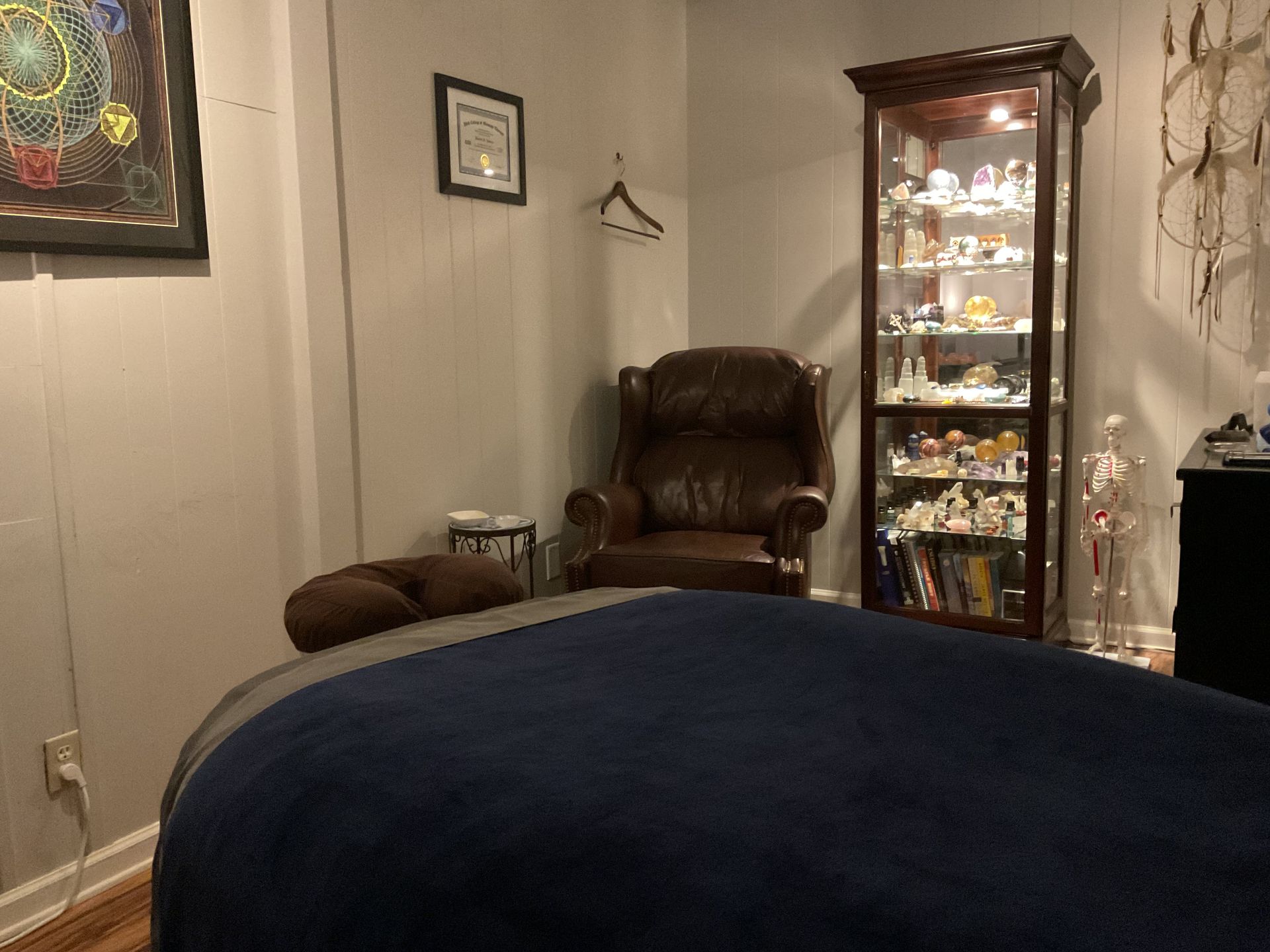 Dim living room with a recliner, glass display cabinet, and a dark blue sofa in the foreground