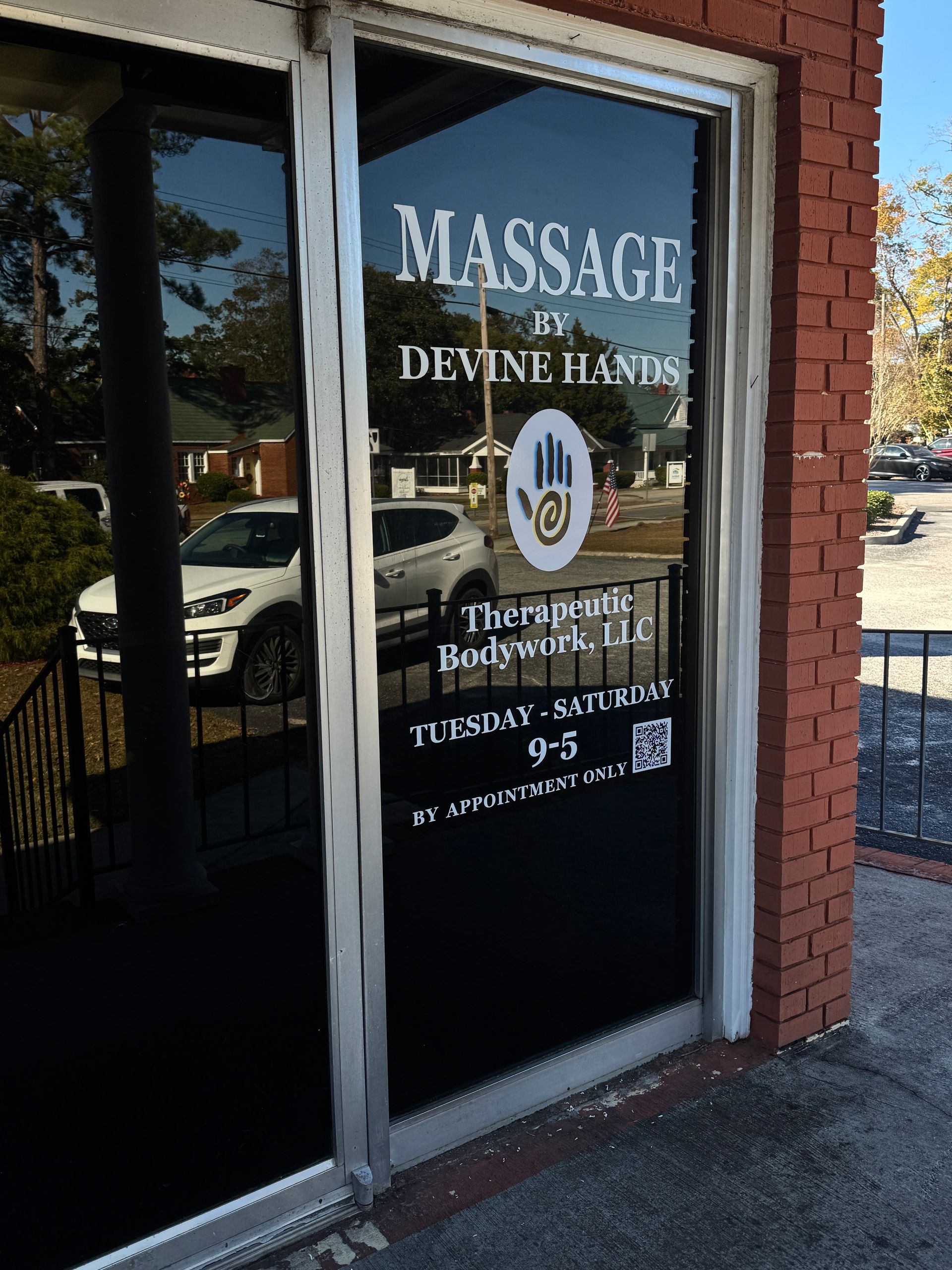 Massage studio storefront with glass door, white lettering, and a red brick exterior.
