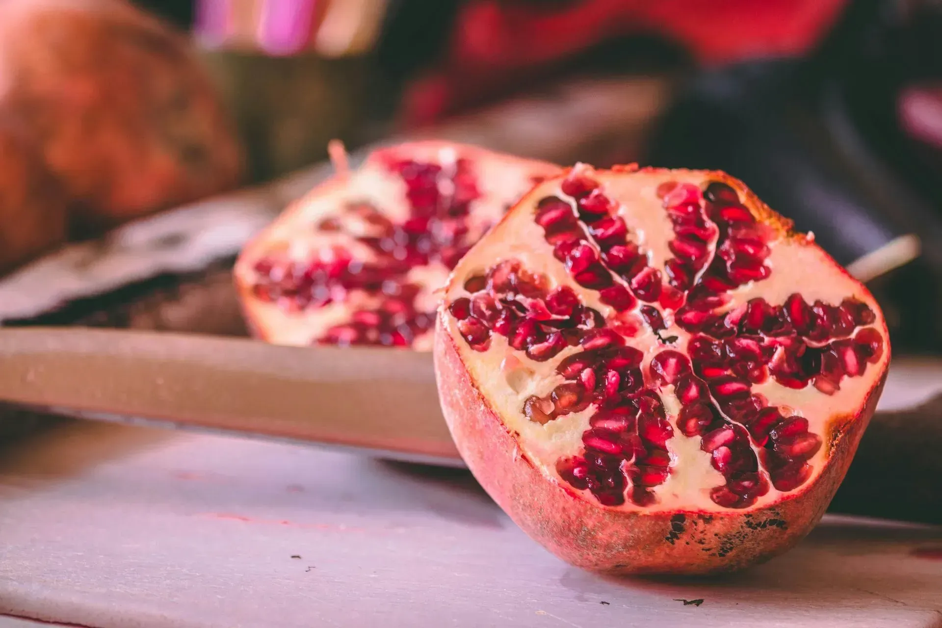 Cut pomegranate halves with bright red seeds on a cutting board