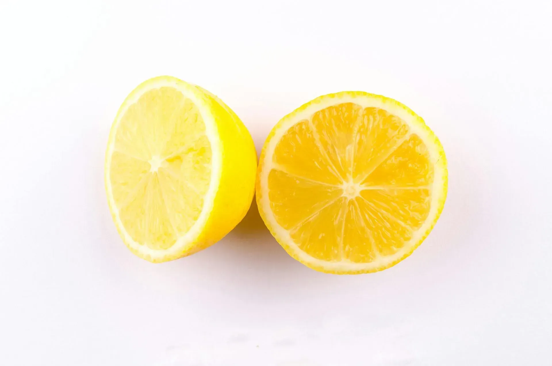 Two lemon halves on a white background, one cut side facing forward and one angled sideways