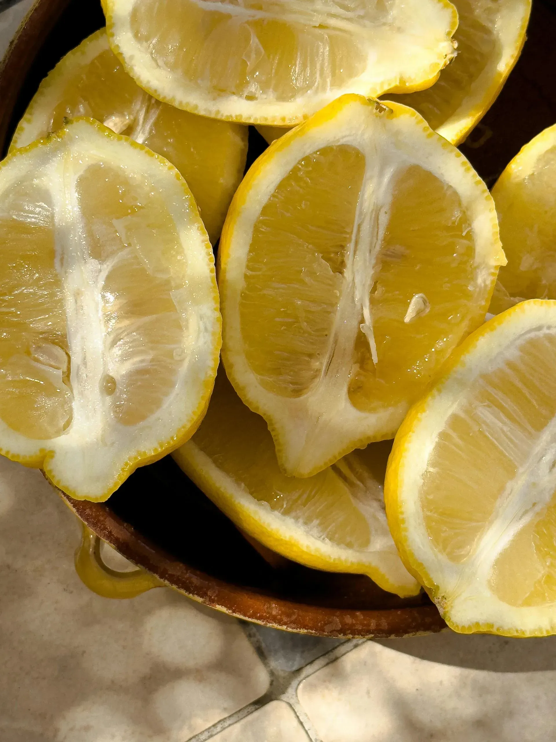 Sliced lemons in a wooden spoon, with bright yellow peel and pale pulp.