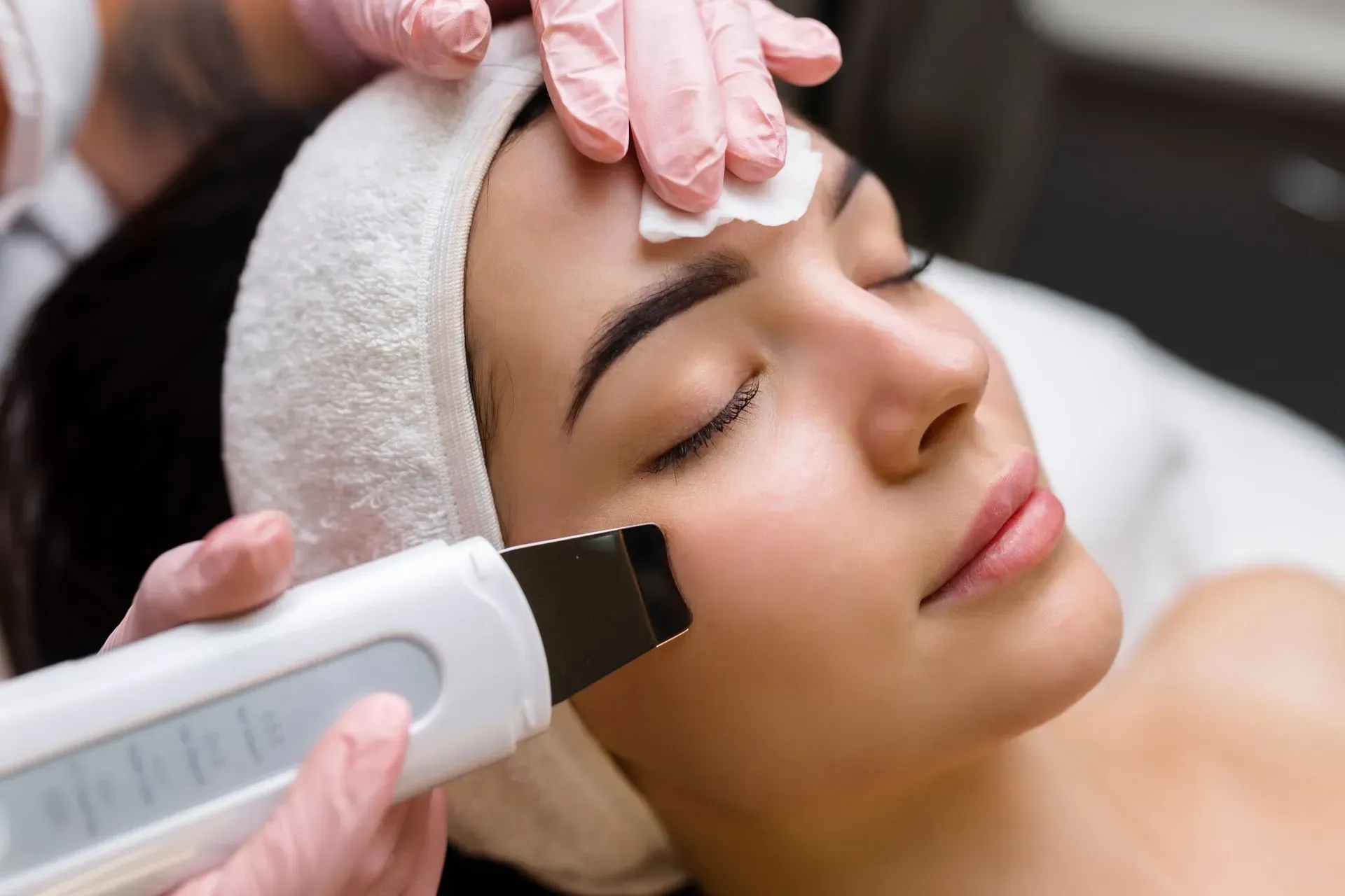 Facial skincare treatment with a handheld cleansing device on a woman’s face