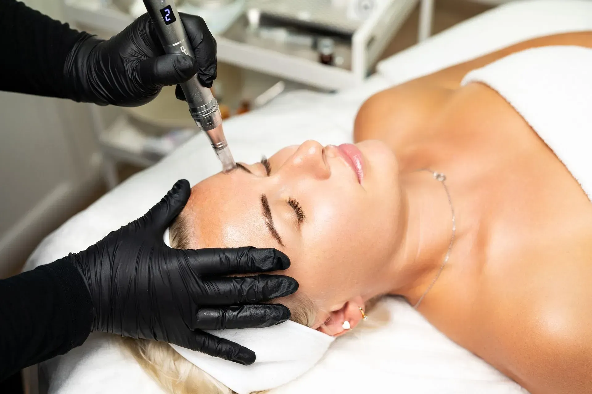 Cosmetic treatment on a woman’s face with gloved hands using a handheld device