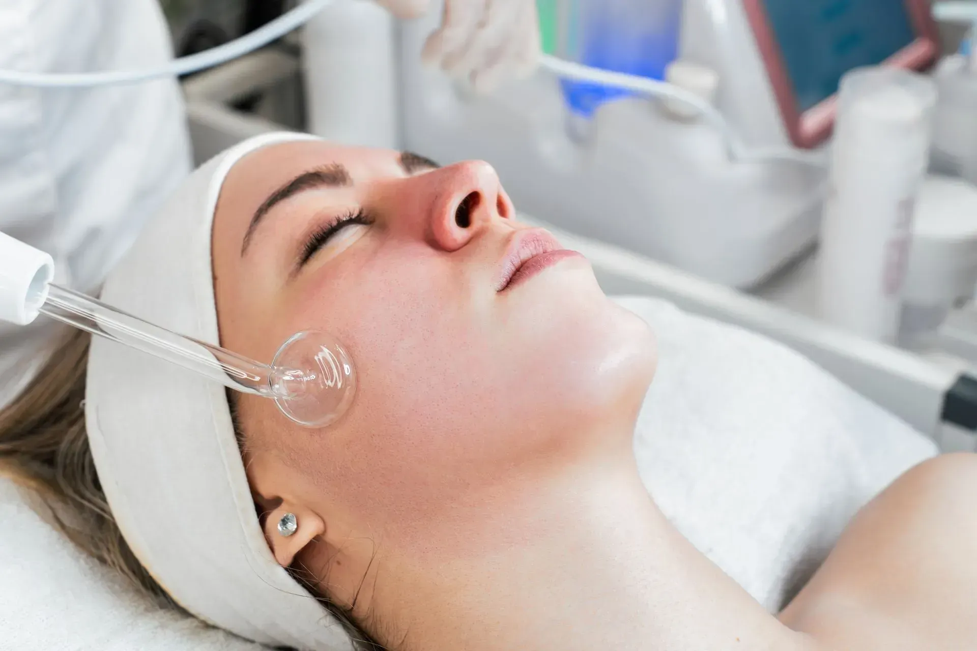 Woman receiving facial treatment with a clear facial wand in a spa setting