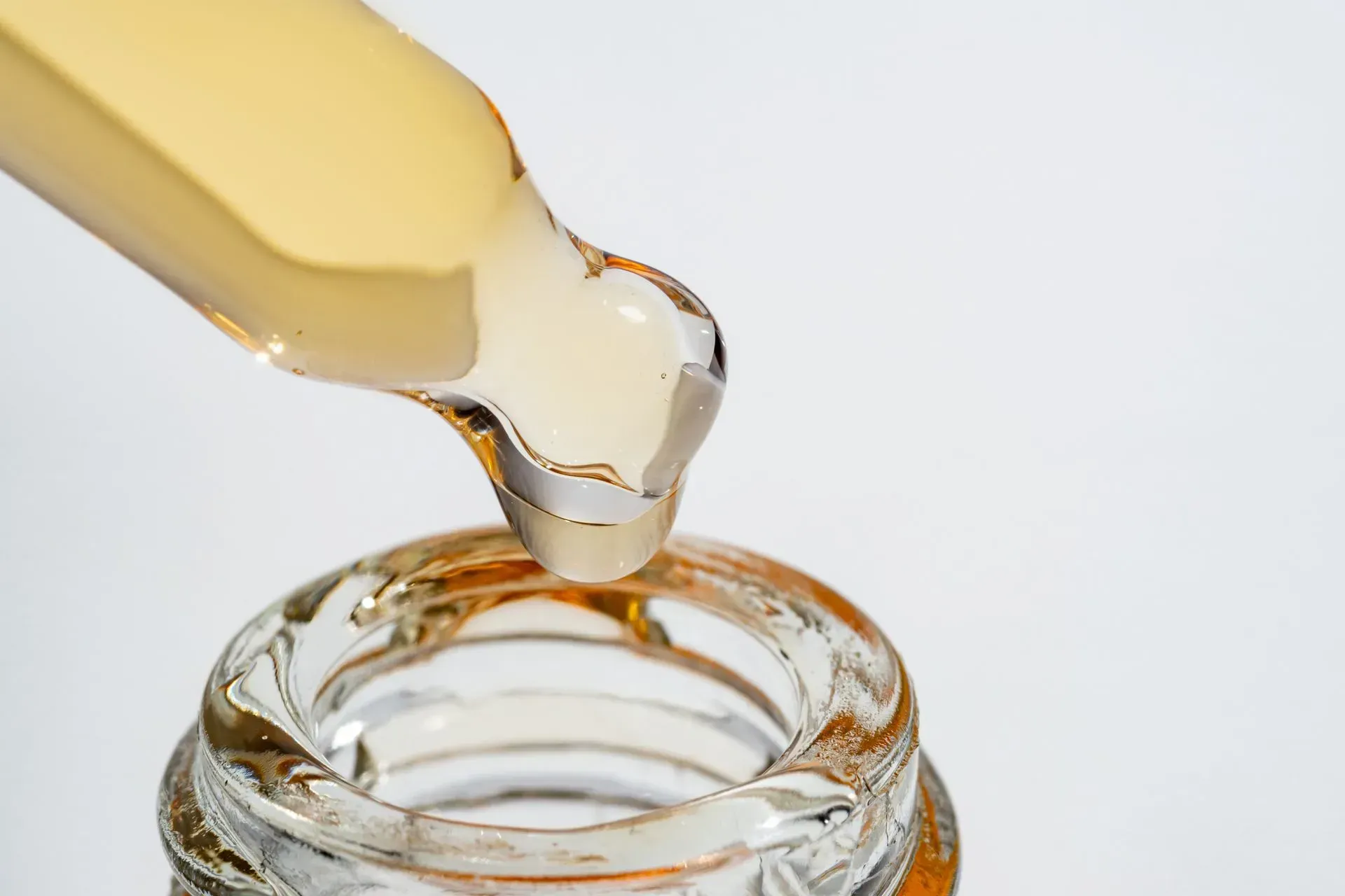Clear liquid dripping from a dropper into a small glass jar