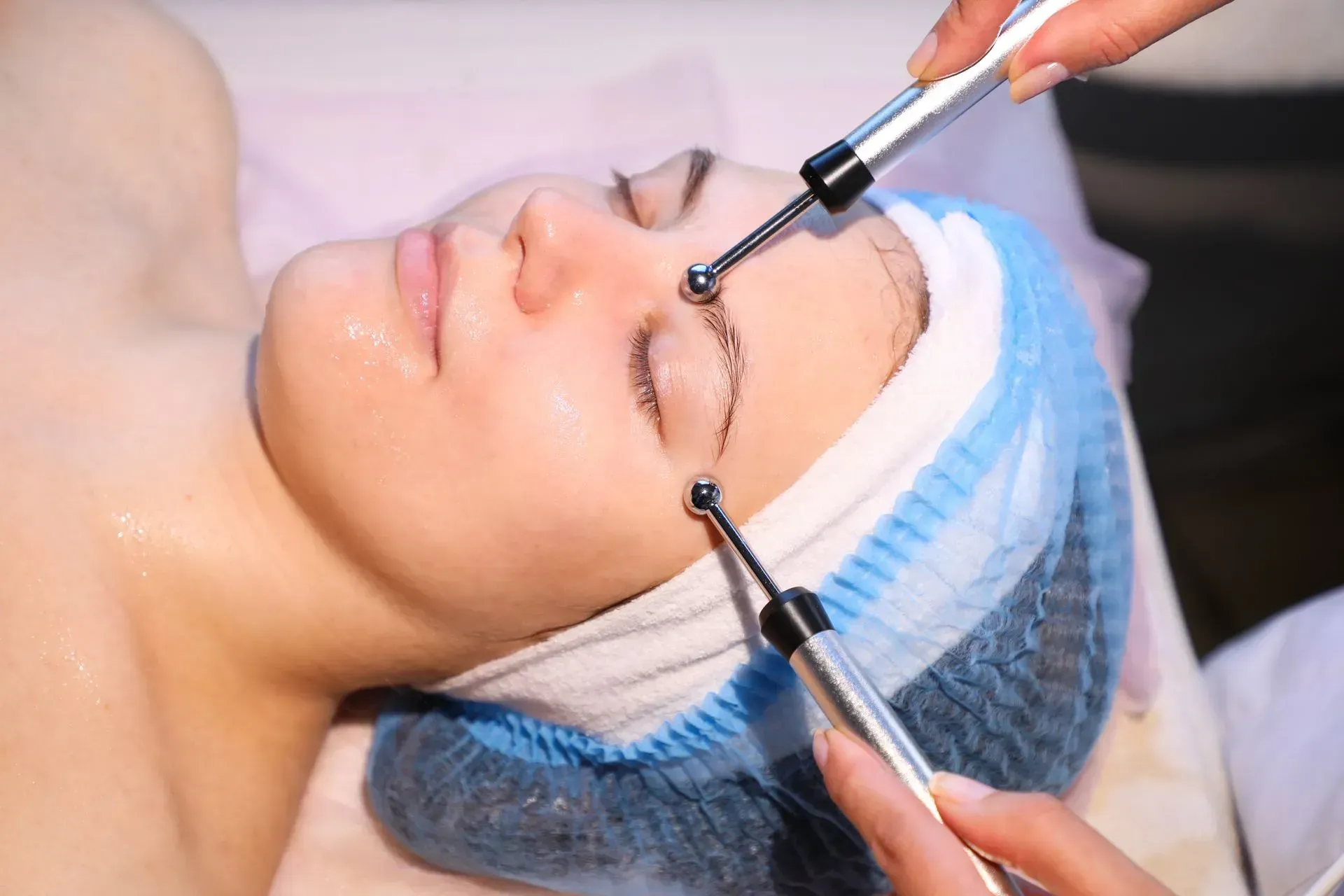 Cosmetic treatment with two tools near a woman’s closed eye in a clinic setting