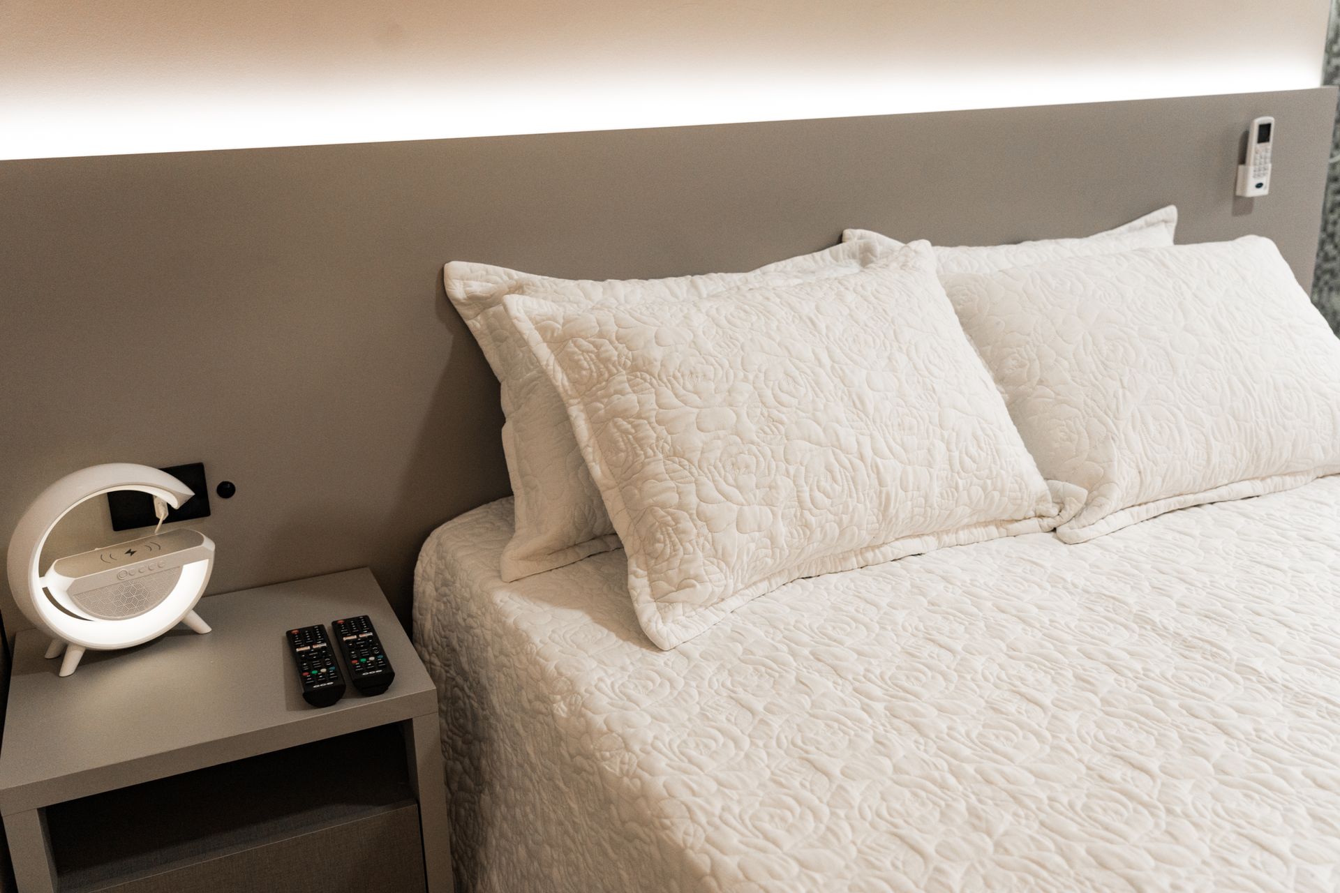 Uma cama com lençóis e travesseiros brancos em um quarto com mesa de cabeceira. MD Recanto Hotel