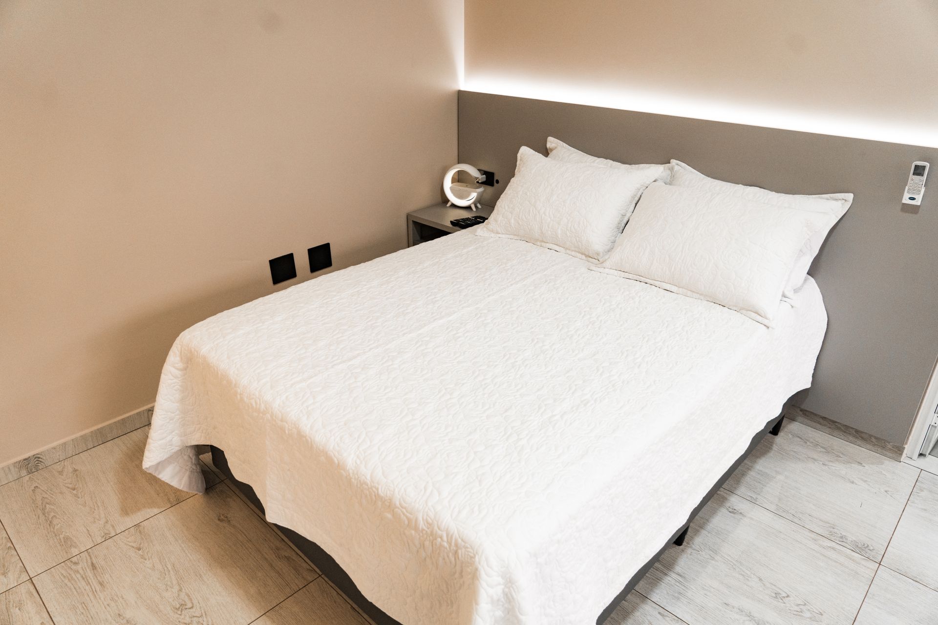 Uma cama com lençóis e travesseiros brancos em um quarto de hotel. MD Recanto Hotel