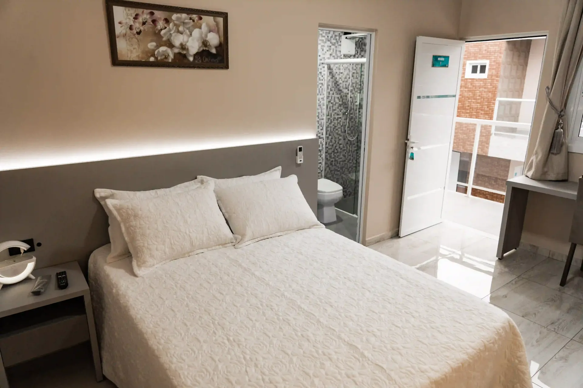 Um quarto com uma cama, mesa de cabeceira e banheiro. MD Recanto Hotel