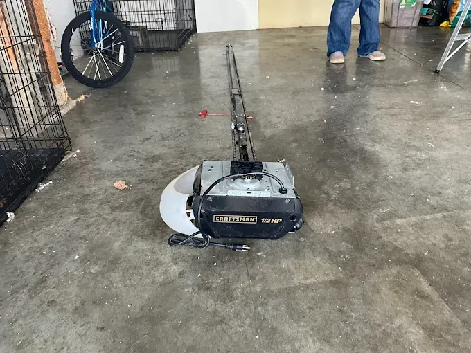 Leaf blower/vacuum on a wet concrete floor in a garage, with a person standing nearby.