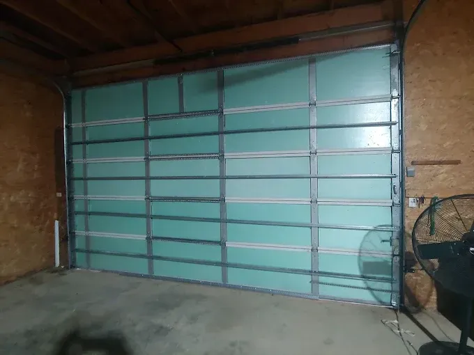 Turquoise garage door with metal frame in a brick-walled interior garage.