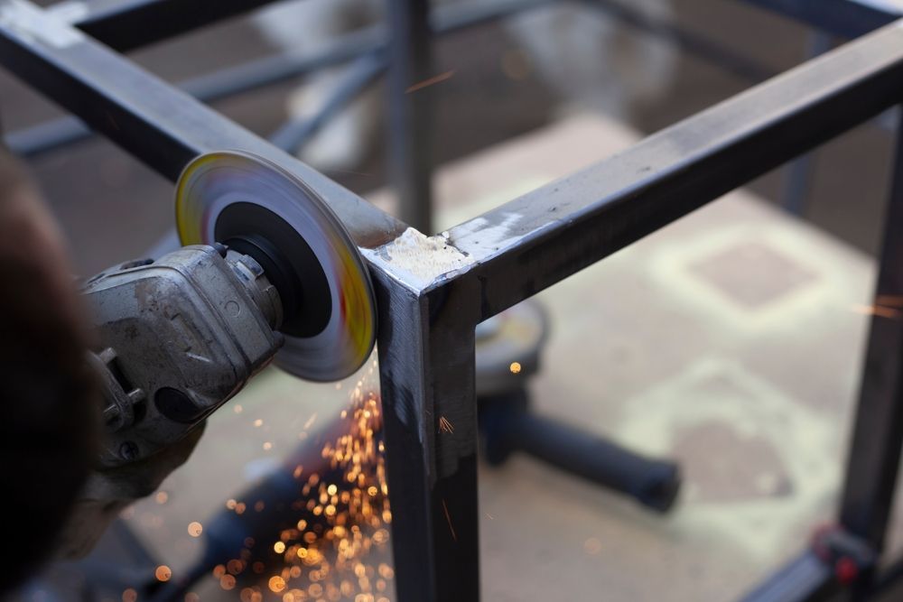 Angle grinder cutting a metal frame, sending sparks at a workshop