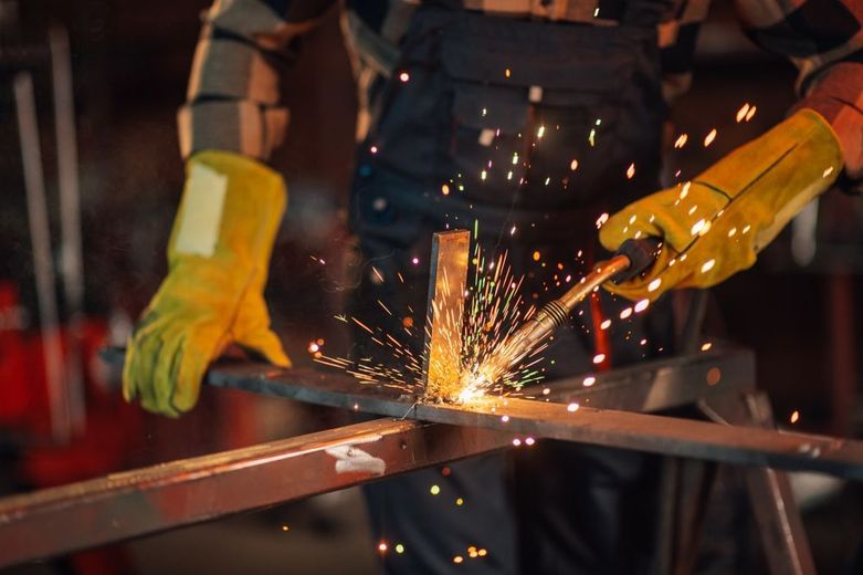 Worker cutting metal with an angle grinder, sending bright sparks in a workshop