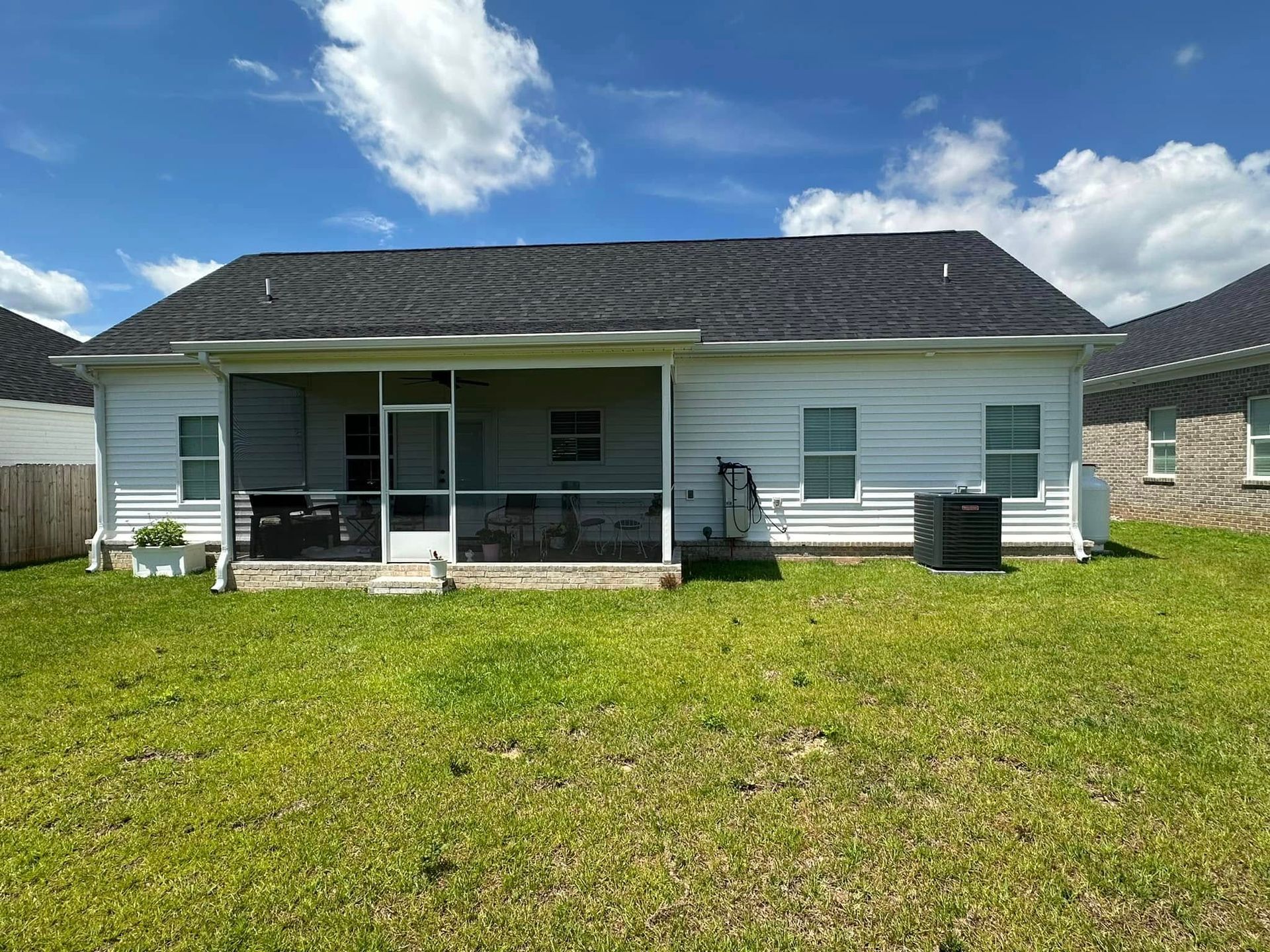 Back view of a white single-story house with a covered patio and grassy yard