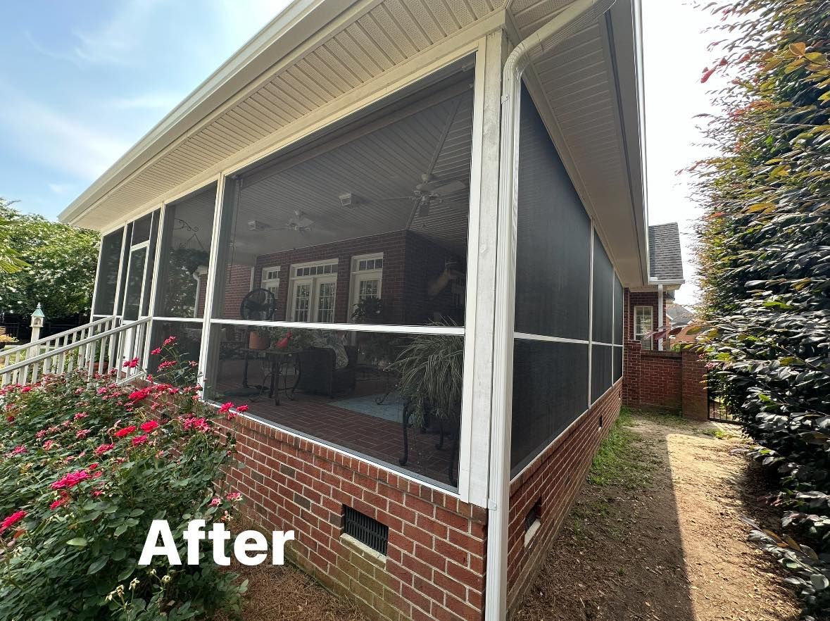 Screened porch with brick base and white trim, viewed from the front with flowers in the foreground.
