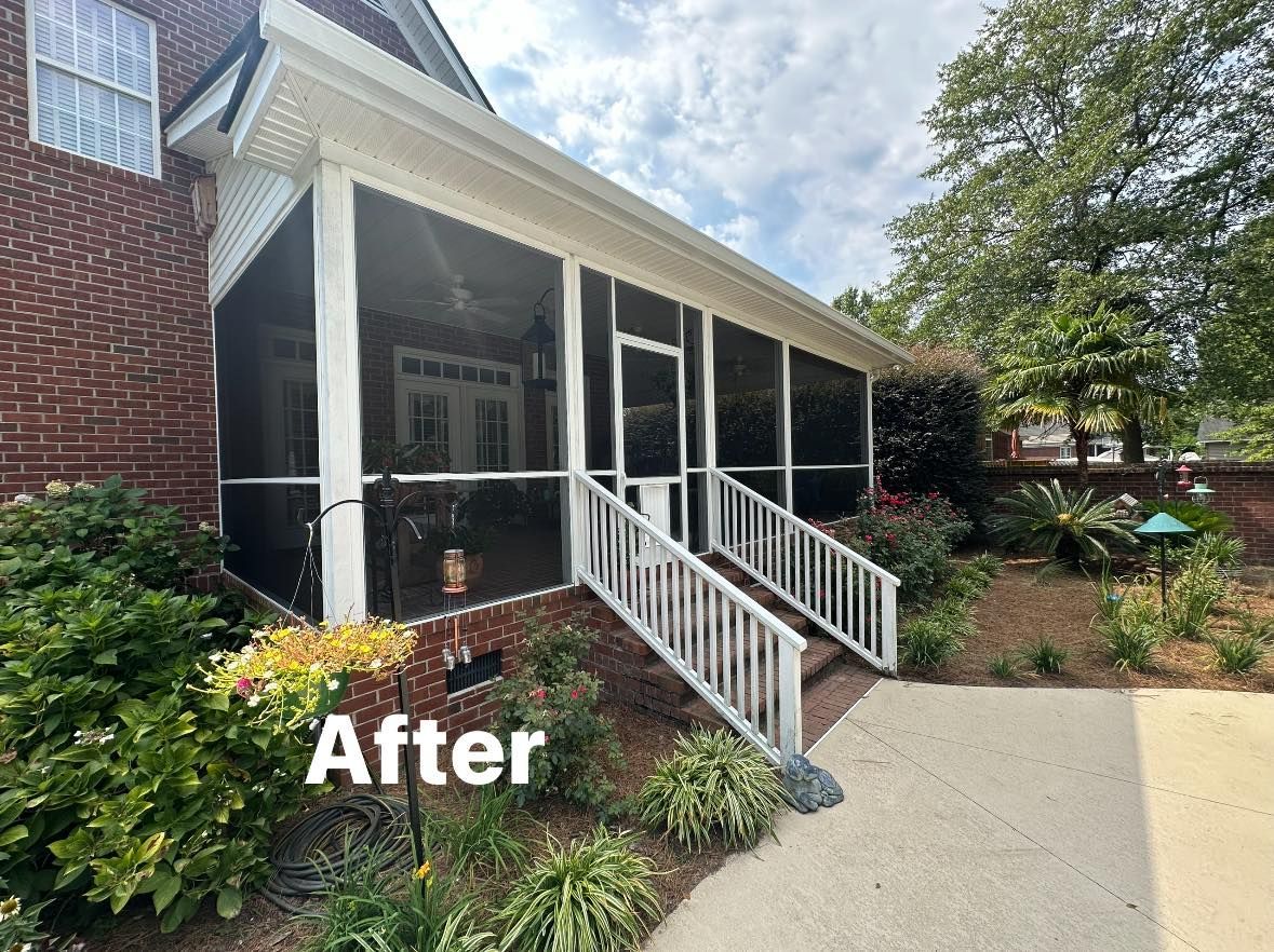 After view of a porch with white railings, black columns, and landscaped garden beside a sidewalk